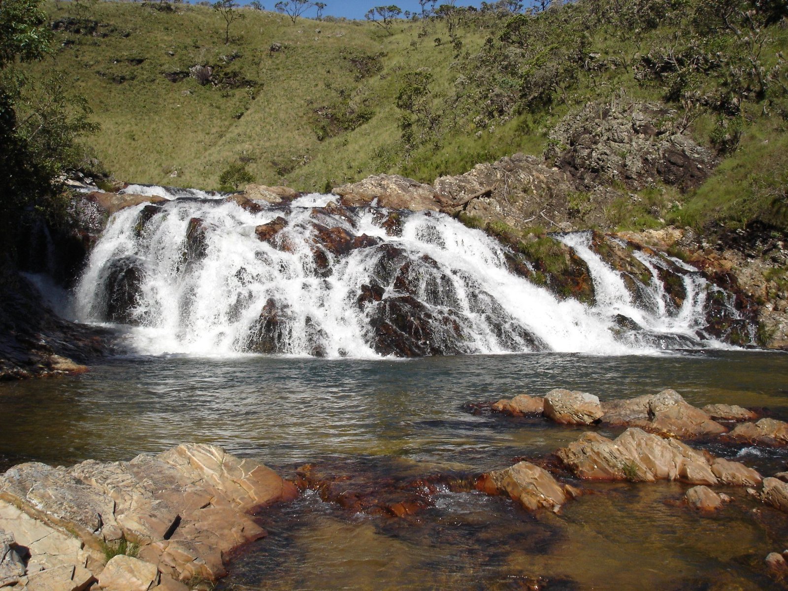 Cachoeira Grinalda, queda larga entre pedras e campo verde
